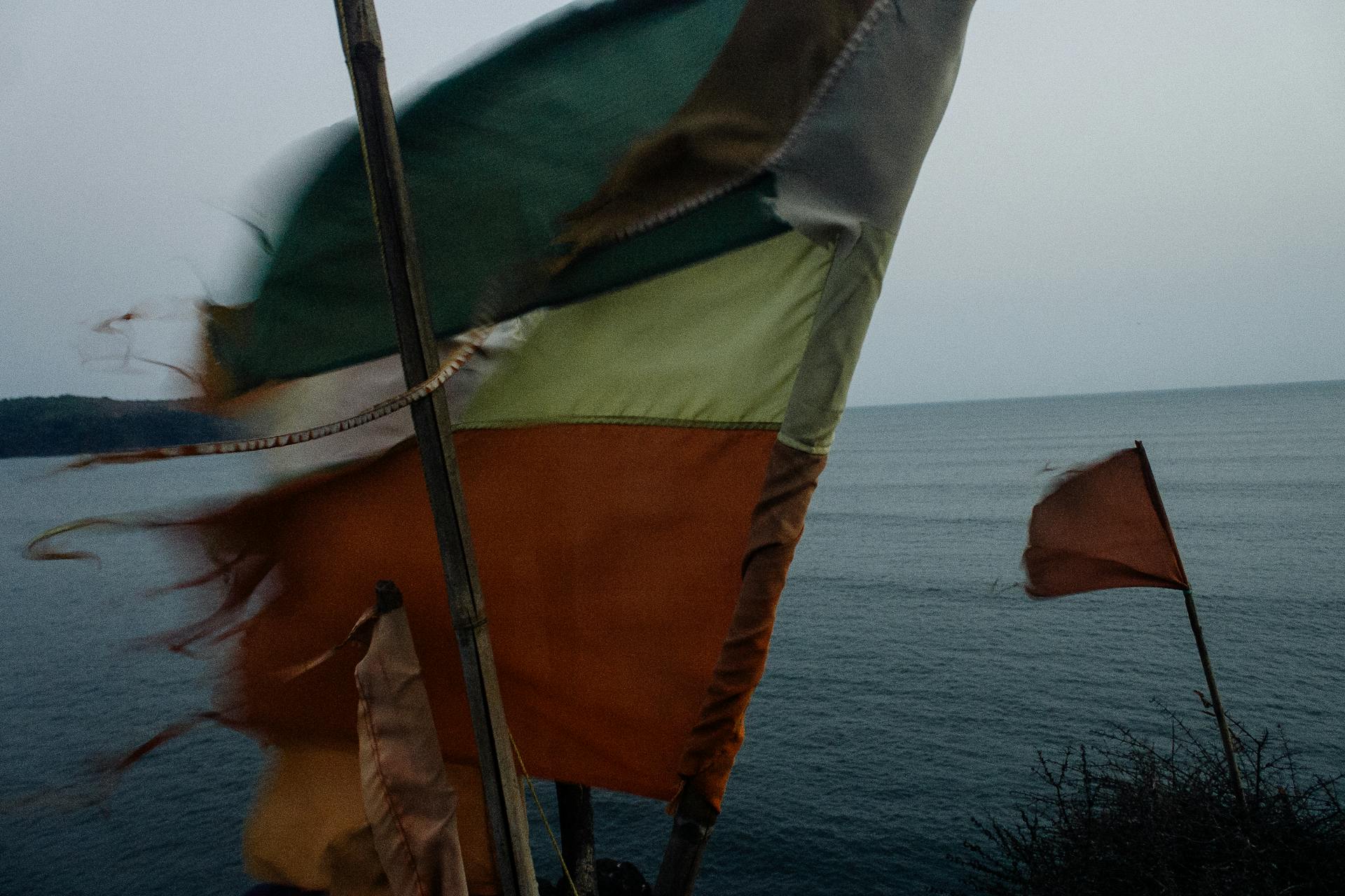 National flag fluttering on flagpole in windy day on shore of rippling sea