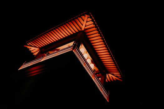 A low-angle view of a beautifully illuminated traditional Chinese architectural structure at night.