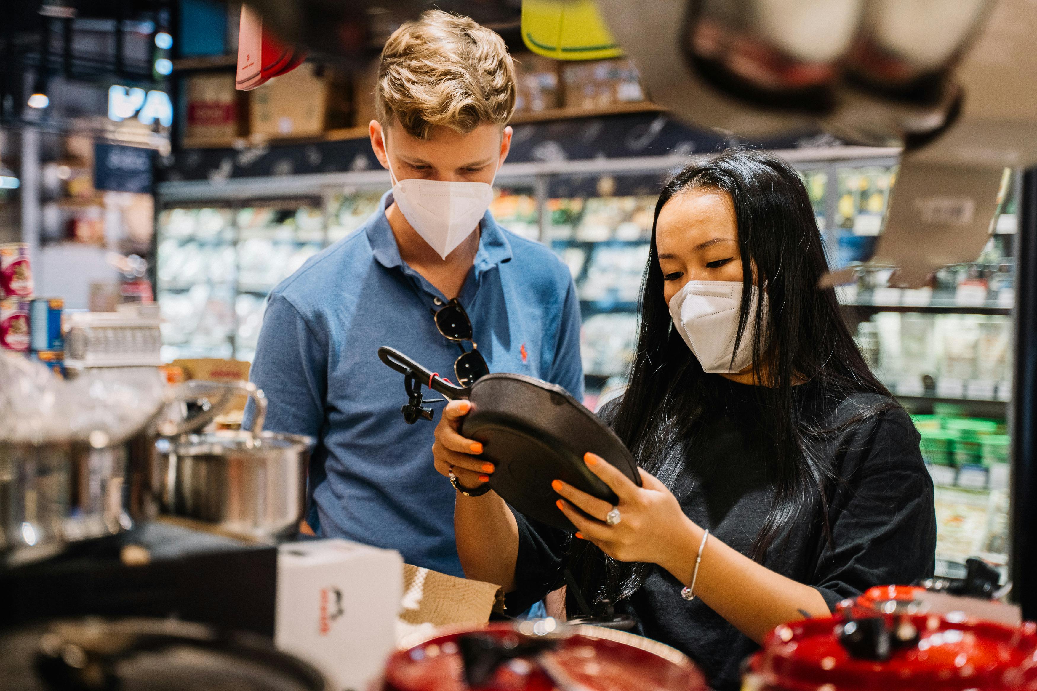 couple wearing face masks looking at kitchenware inside a supernarket