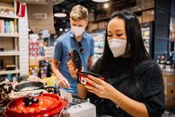 一对夫妇戴着口罩在商店购买厨具，这是预防大流行的例证