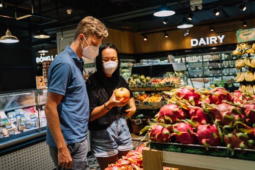 Free A couple wearing face masks shopping for fresh fruits at an indoor supermarket. Stock Photo