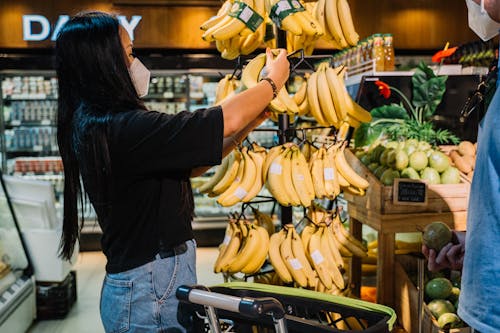 Woman With Face Mask Holding Yellow Banana Fruit