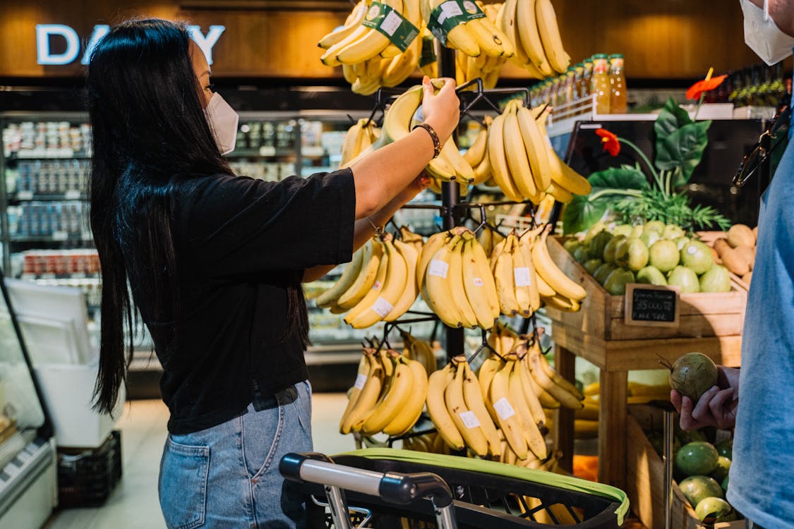 Woman in Blue Denim Jacket Holding Yellow Banana Fruit