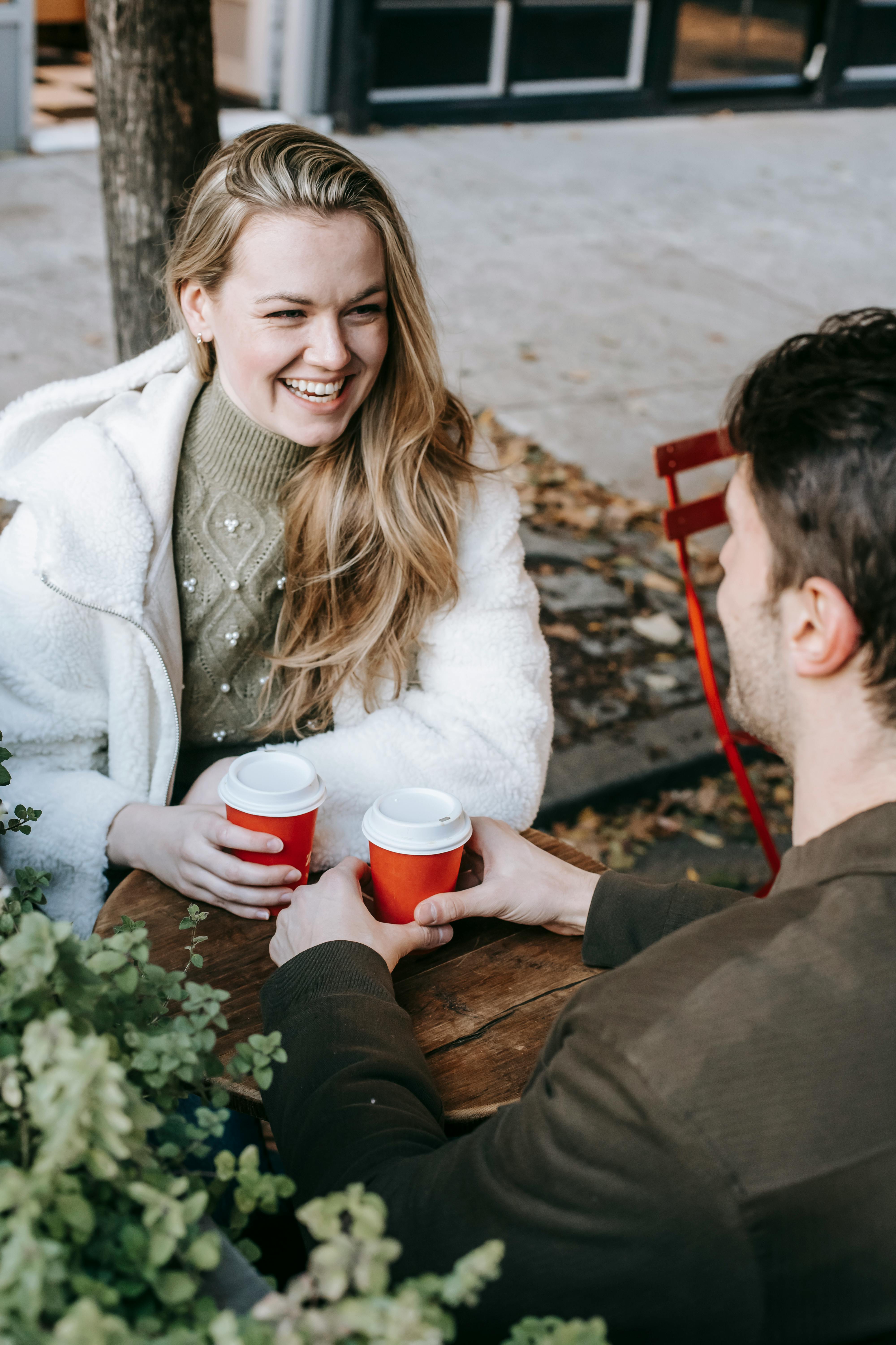 Happy couple having a cheerful conversation over coffee outdoors on a sunny day.