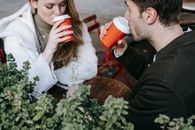 Crop man and woman drinking coffee to go in street cafeteria