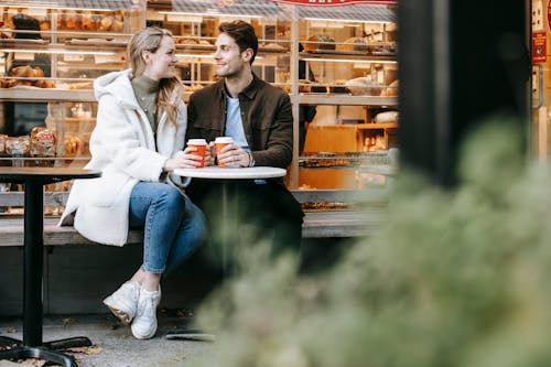 Free Happy young man and woman having hot tea in cosy cafe Stock Photo