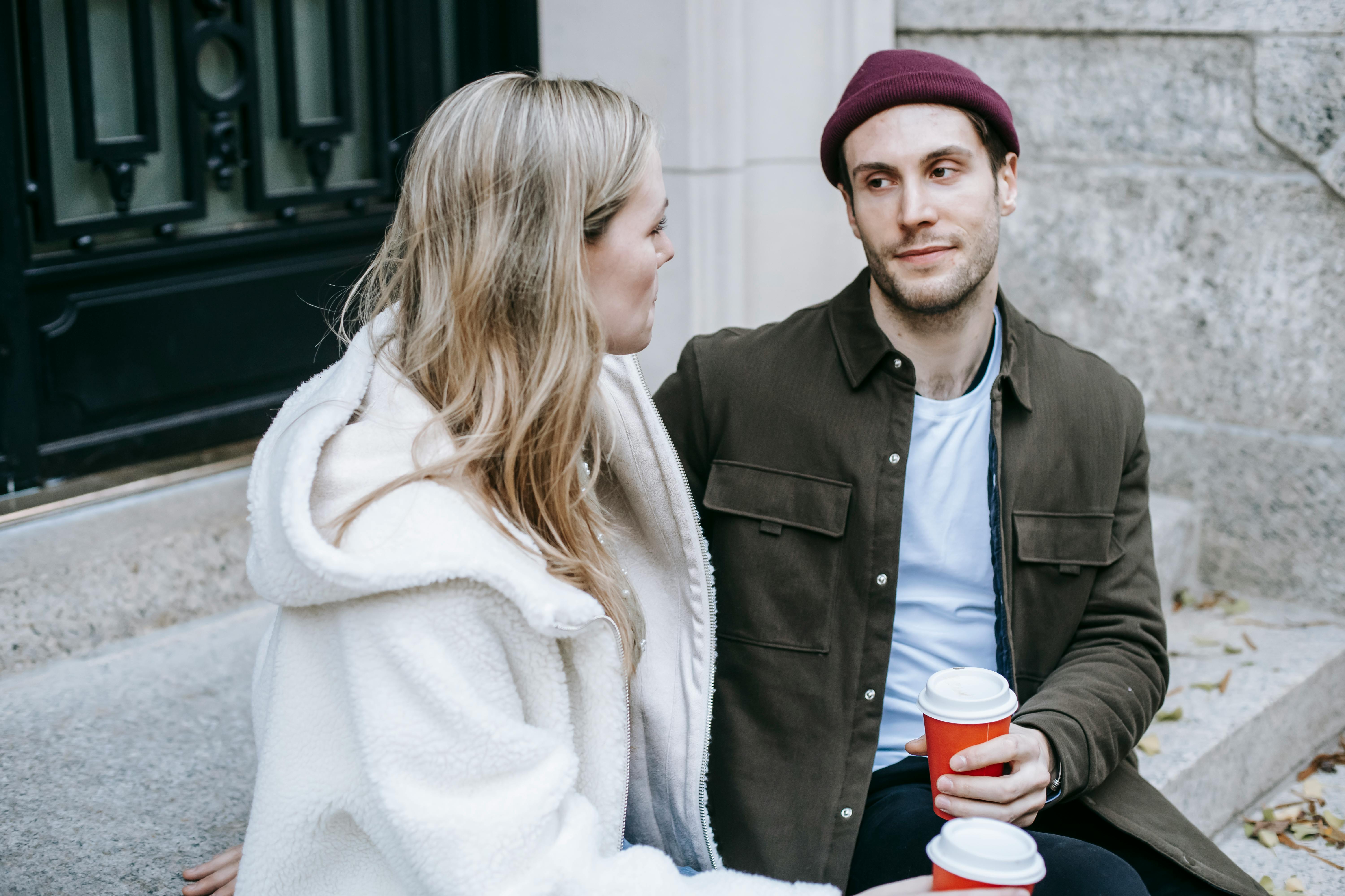 young man and woman speaking sitting on steps beside house