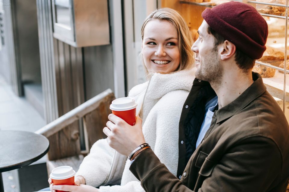 A smiling couple having coffee in a bakery on a first date
