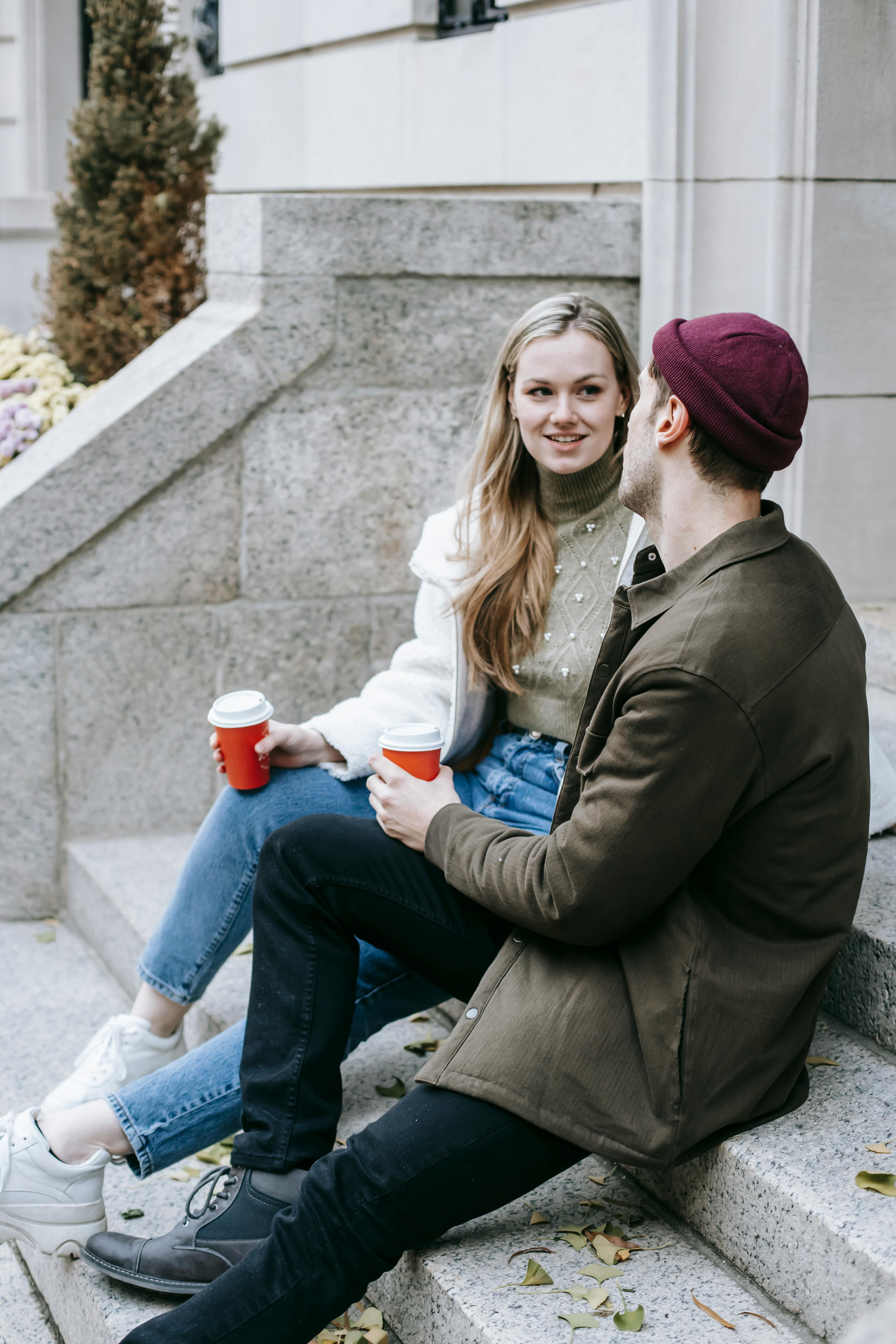 happy couple drinking coffee together on street