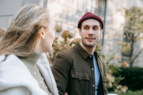 Young smiling man in casual wear and girlfriend walking on street in sunny day looking at each other