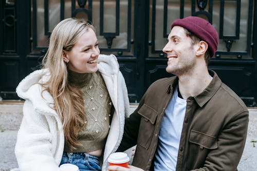 Free Happy young man and woman drinking coffee near big building Stock Photo