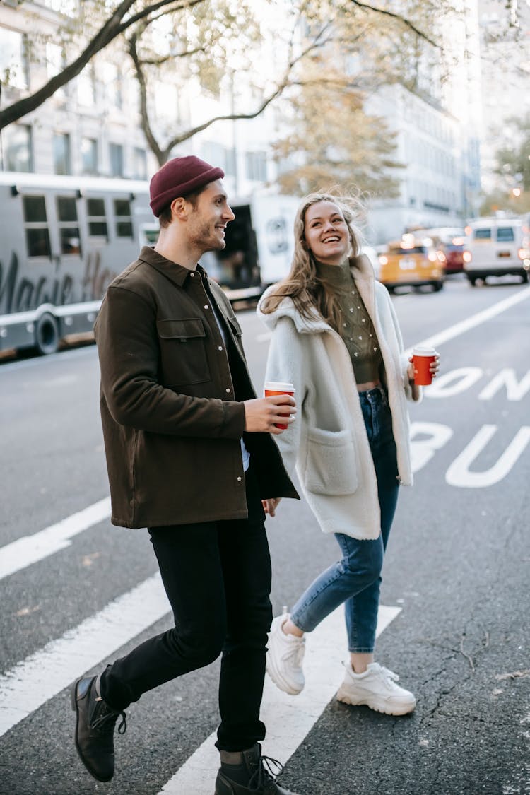 Couple Walking On Street With Coffee Cups