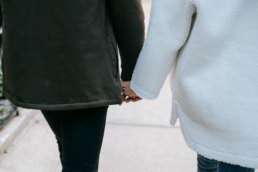 一对夫妇穿着暖和的外套，手牵着手在城市里浪漫地散步