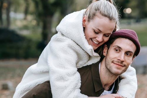 Free Smiling man giving piggyback ride to beloved woman in park Stock Photo