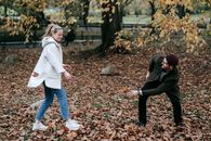Cheerful young couple playing with fallen leaves in park
