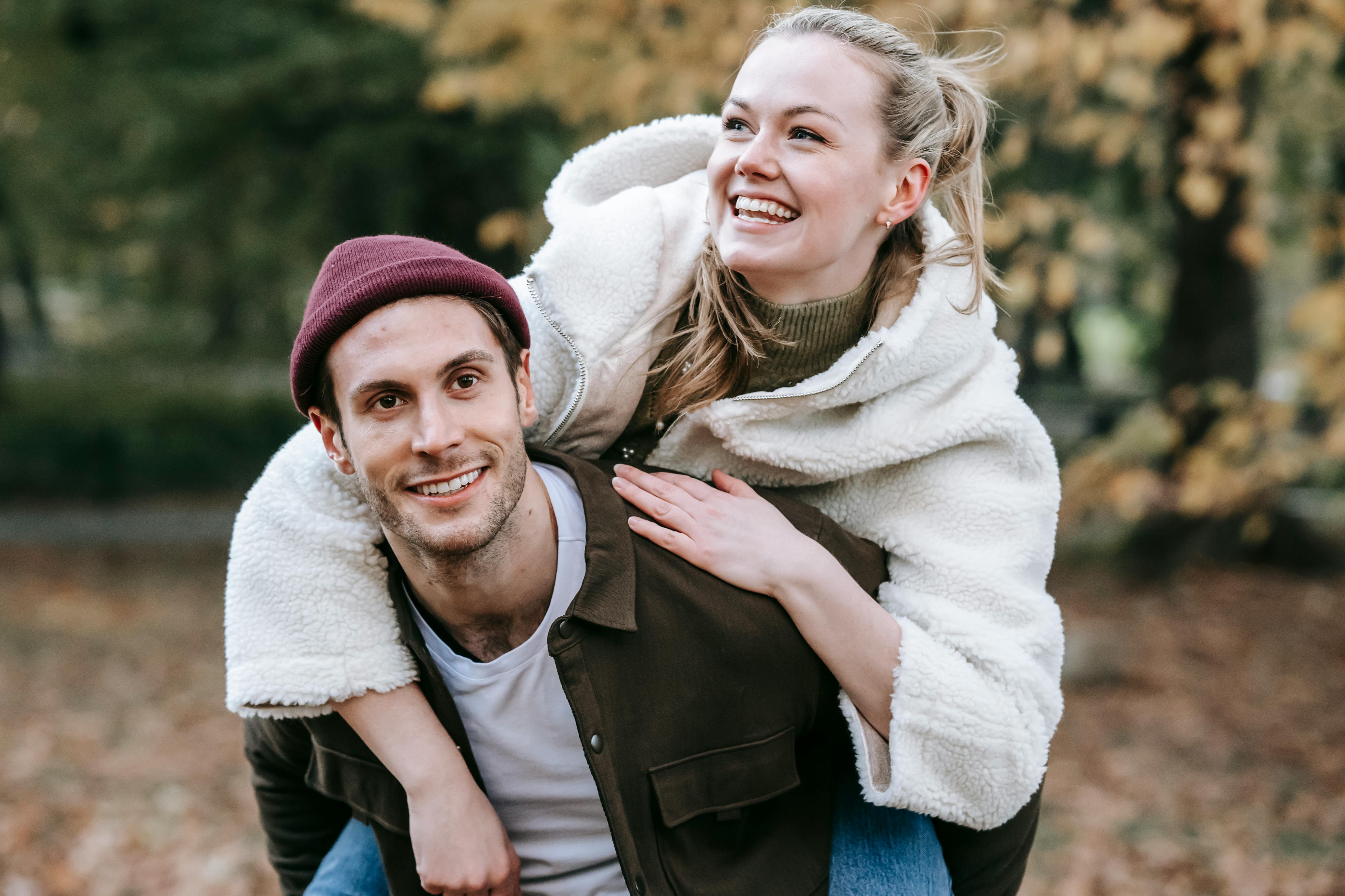 cheerful young couple hugging and having fun in autumn garden