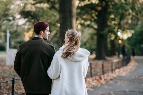 Young trendy couple chatting and strolling in park on autumn day