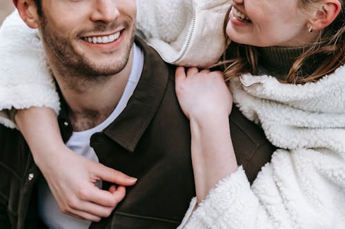 Free Crop anonymous couple in warm casual clothes cuddling each other and smiling together Stock Photo