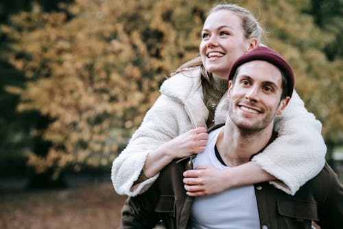 Cheerful woman holding on to boyfriends head while having piggyback ride  stock photo