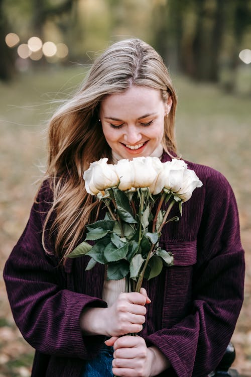 Happy woman smelling white roses