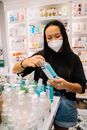 一名亚洲妇女戴着口罩在药房选购洗手液，以促进卫生和安全