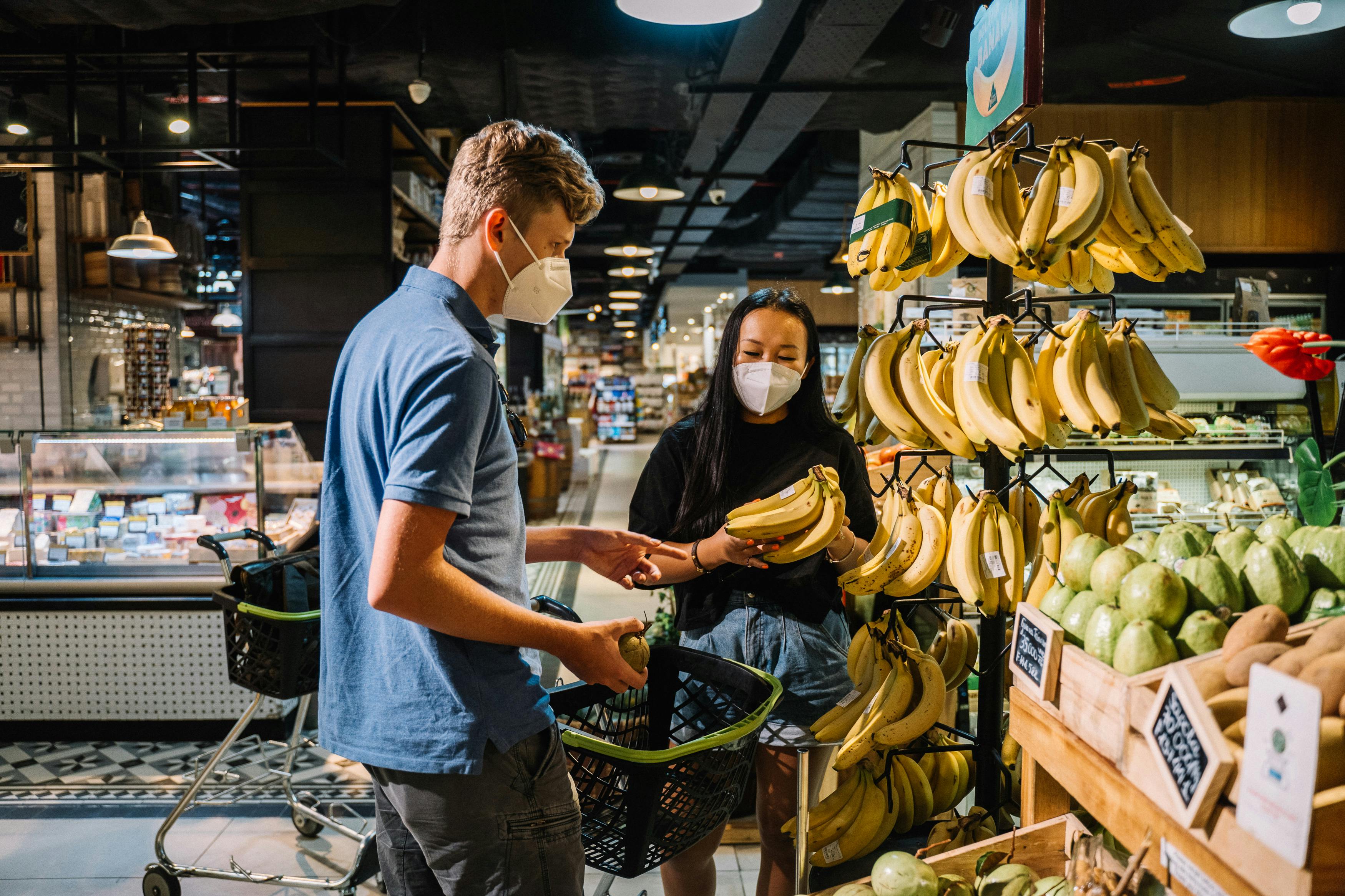 couple wearing face masks buying fresh bananas