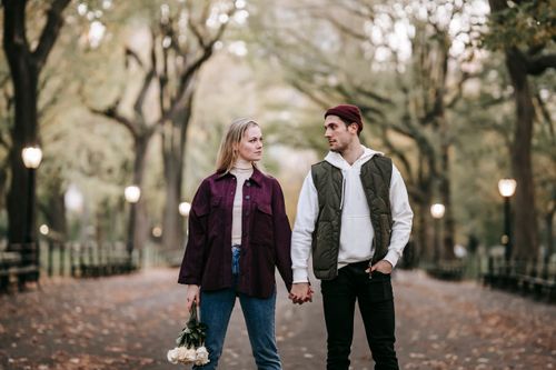 Free Loving couple with bouquet of white roses looking at each other on blurred background of park with trees Stock Photo