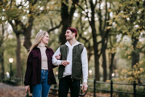 Free Cheerful couple smiling and walking in park with green trees and lights on blurred background Stock Photo