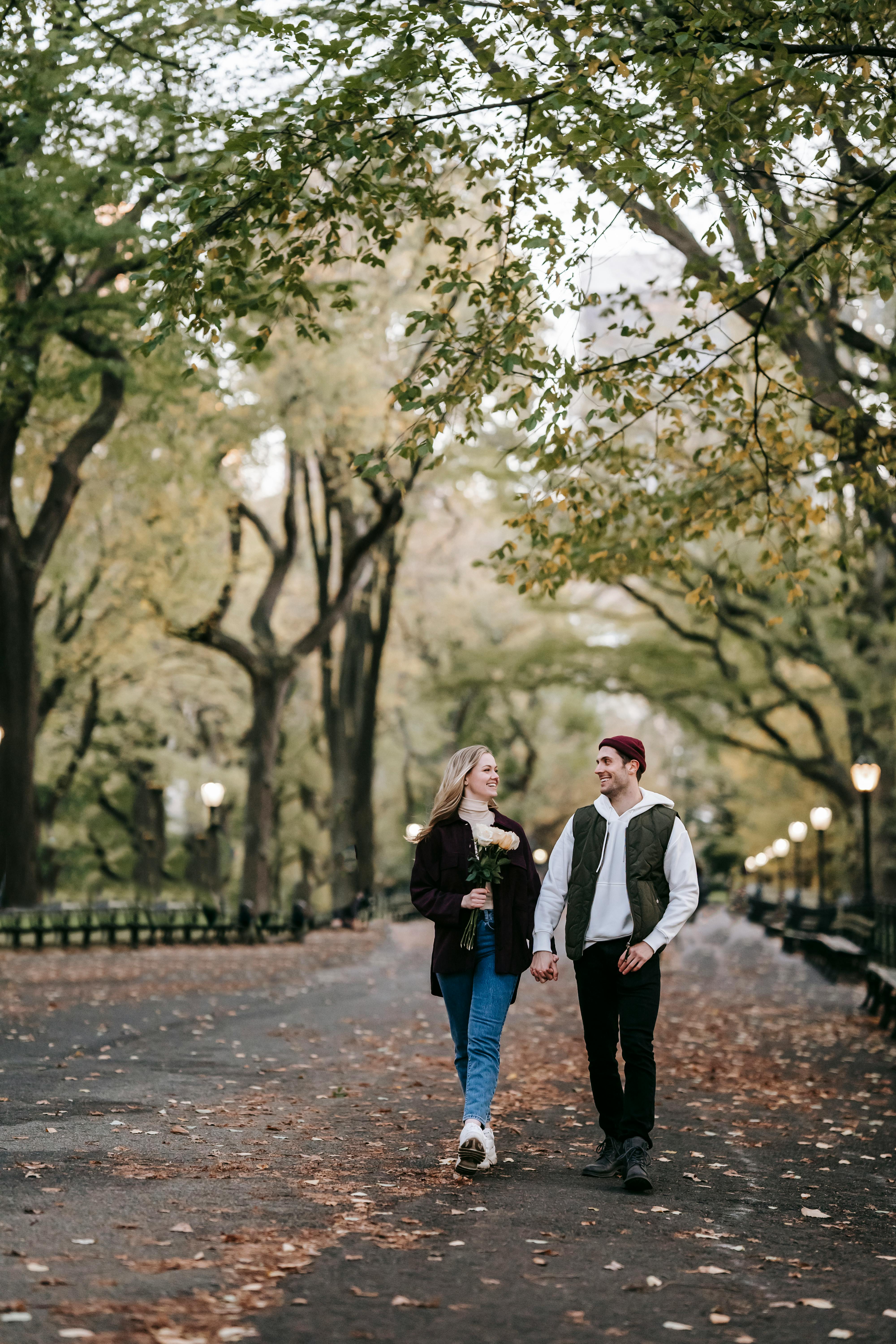 happy couple with bouquet of roses promenading in park