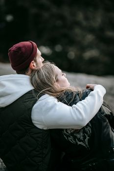 一名穿着休闲装的男子拥抱着梦幻般的女伴，目光却移向模糊的背景