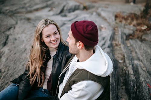 Free Positive young couple sitting on stone in park Stock Photo