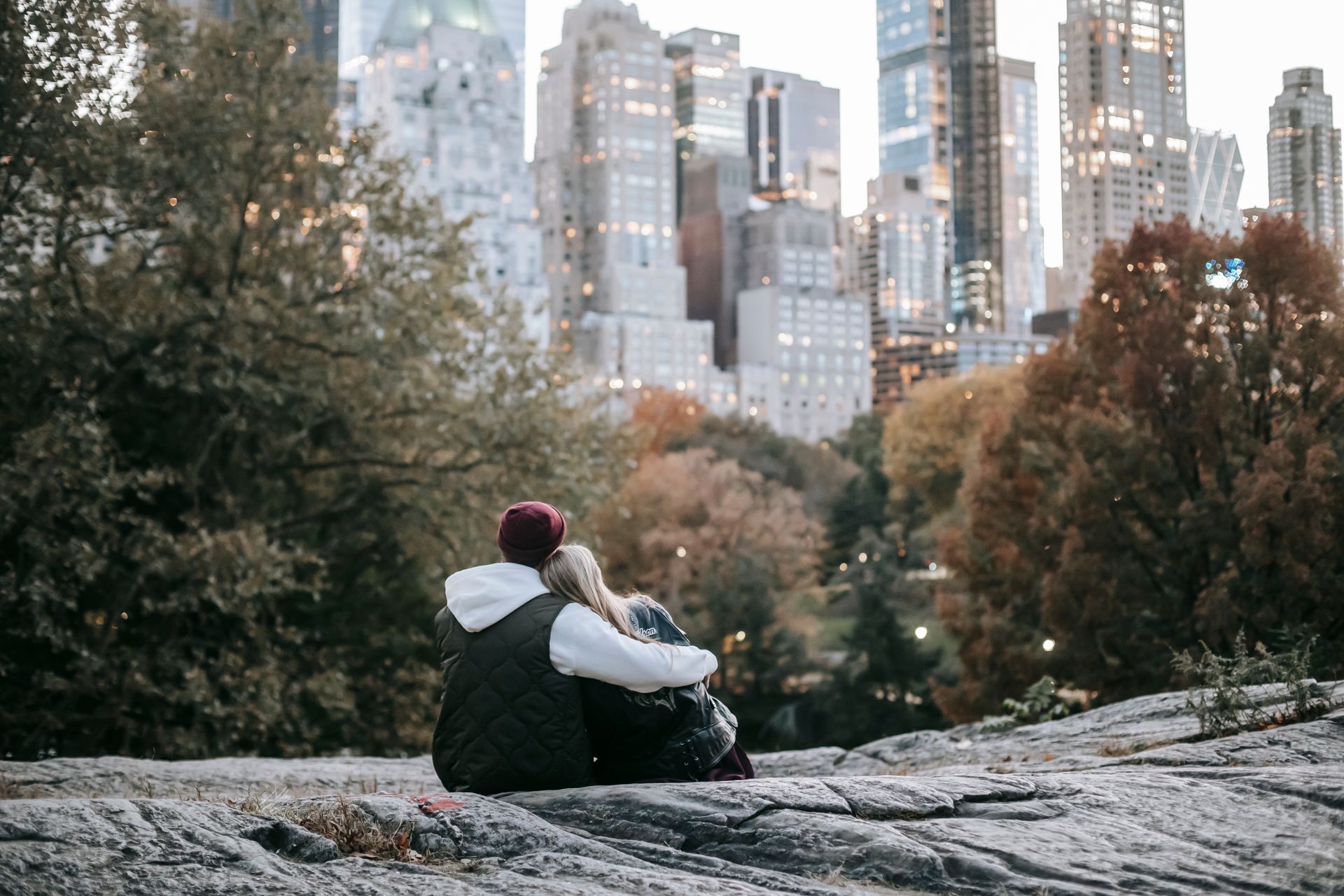 Romantic anonymous couple sitting on stony ground in city