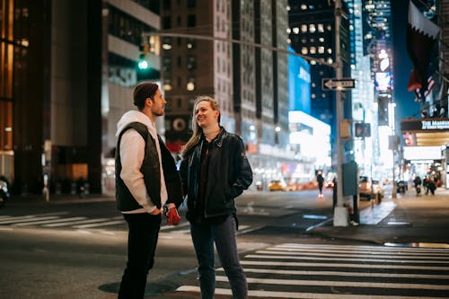 Cheerful couple standing on crosswalk at night time