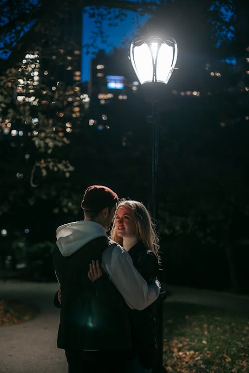 Free Romantic couple hugging in park at night Stock Photo