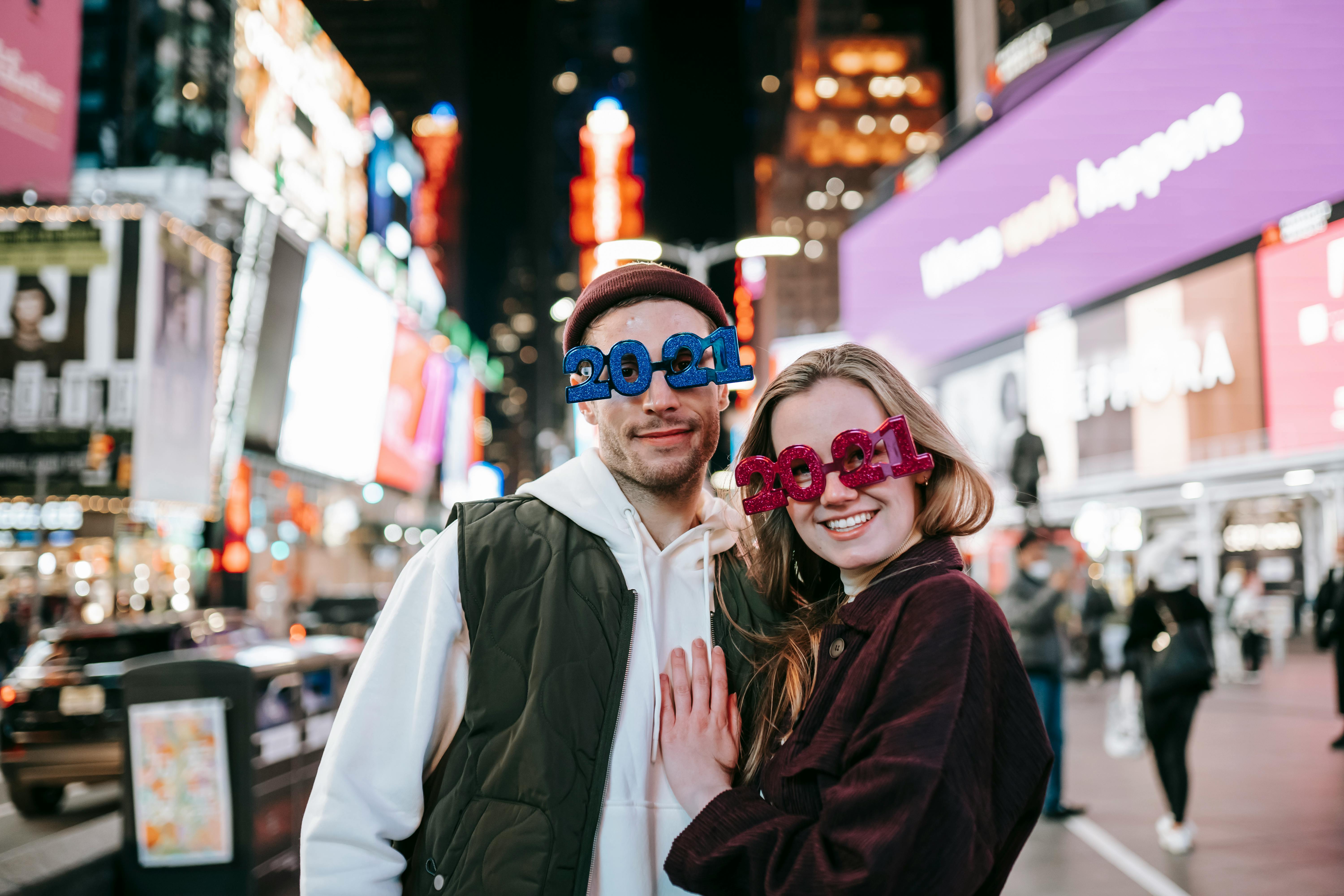 positive couple in stylish glasses hugging on street