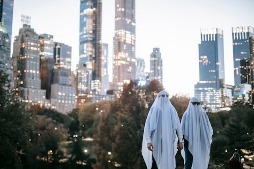 Unrecognizable couple in ghost costumes in city