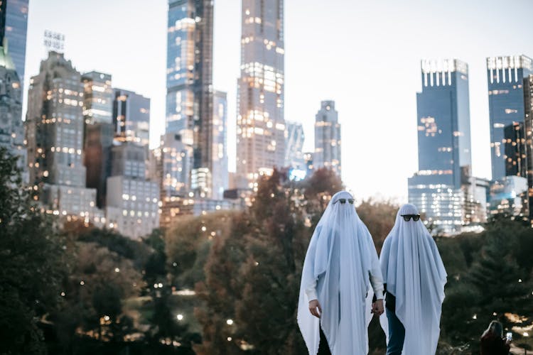 Unrecognizable Couple In Ghost Costumes In City