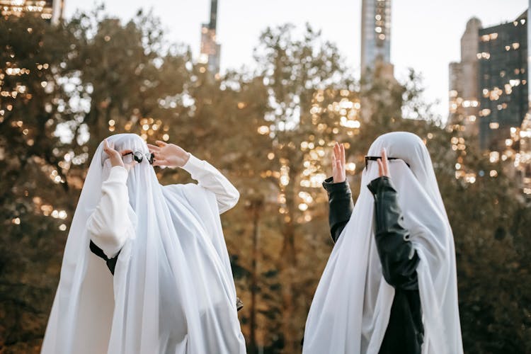 Cheerful Anonymous Couple In Ghost Costumes In Park