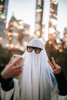 一个穿着幽灵服装的人，以城市天际线为背景庆祝万圣节