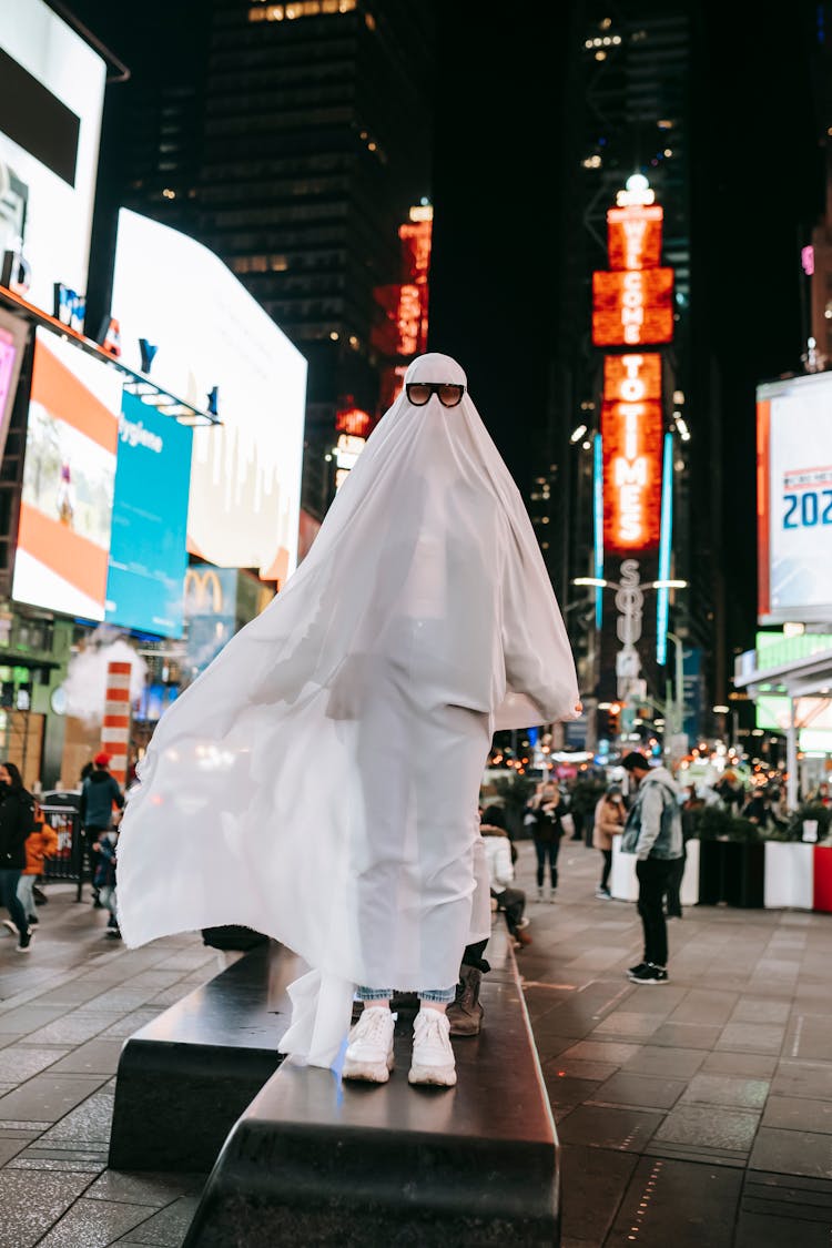 Unrecognizable Person In Ghost Costume On Illuminated Street At Night