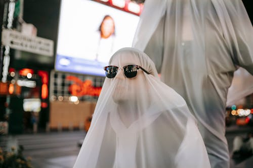 Anonymous couple in ghost costume on night square