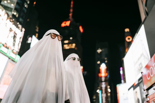 夜晚，两个穿着幽灵服装、戴着太阳镜的人出现在城市街道上