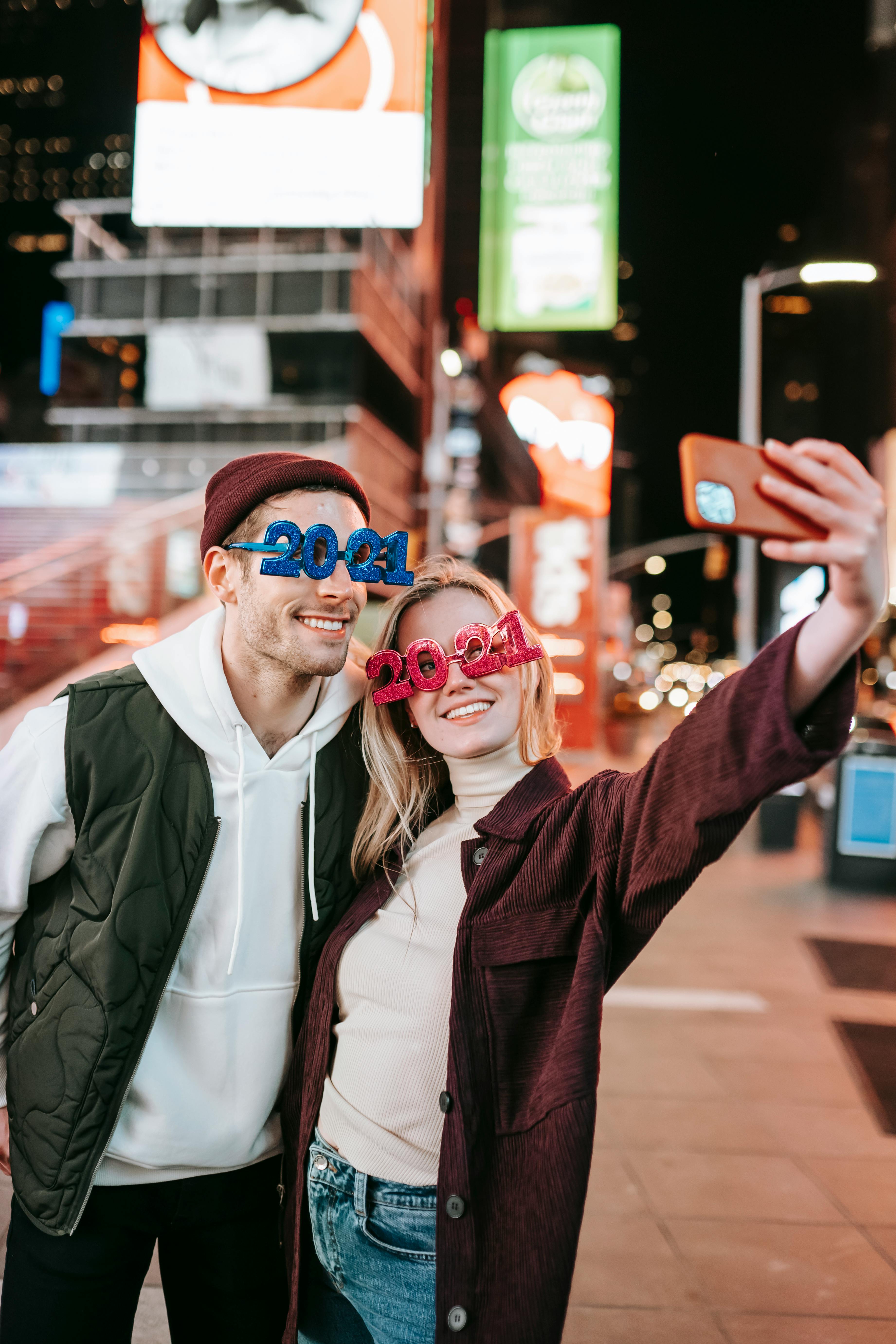 cheerful couple in trendy glasses taking selfie on street