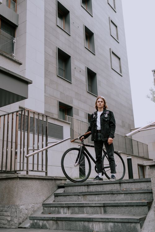 Free Young man with fixie bike standing on stairs in a stylish urban environment. Stock Photo