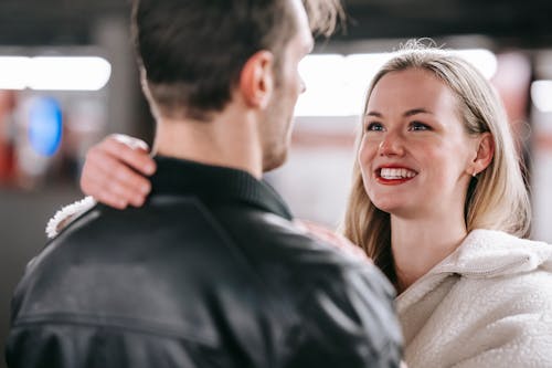 Crop cheerful couple hugging tenderly while toothy smiling and looking at each other