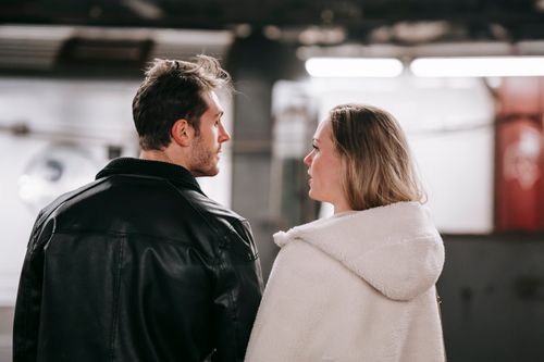 Free Back view of young couple in casual clothes standing close and looking at each other Stock Photo