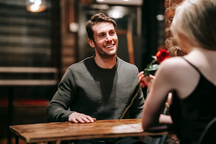 Happy Couple Sitting At Table In Cafe During Date