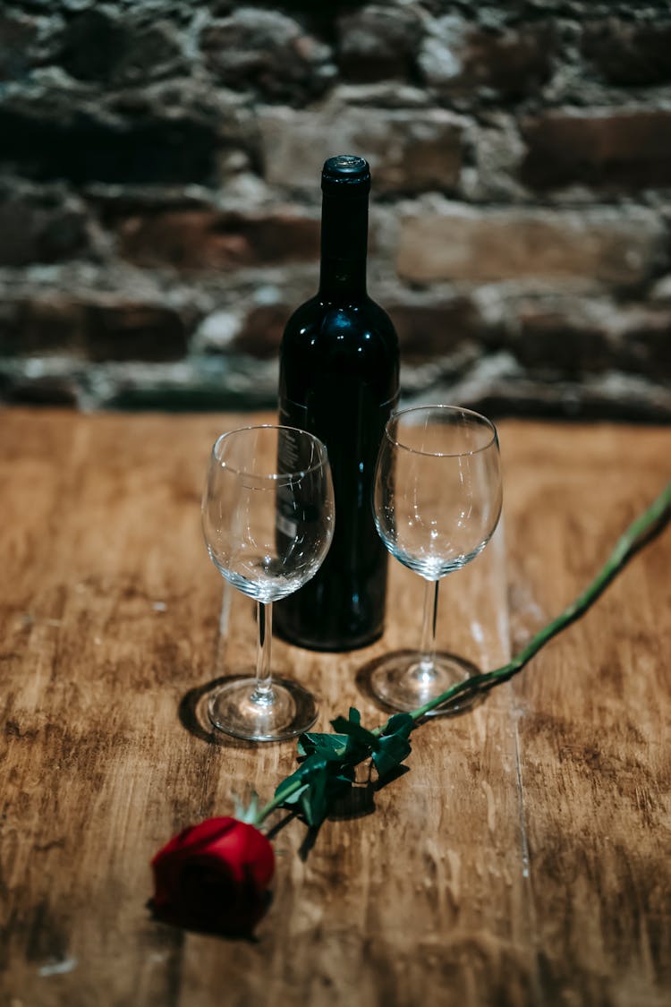 Bottle Of Wine Near Glasses With Rose On Table