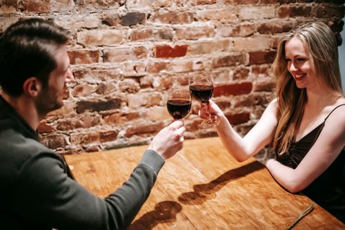 Smartly dressed couple toasting red wine at a restaurant table on a first date