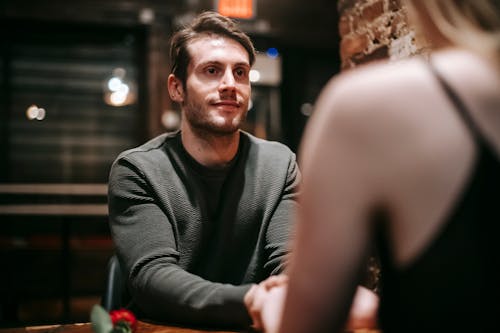 Free Young man in casual clothes sitting at table in modern cafe with girlfriend Stock Photo